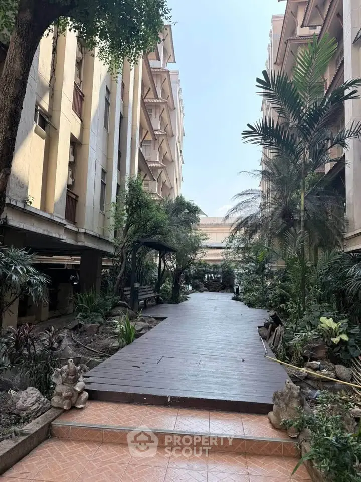 Charming garden pathway between residential buildings with lush greenery and serene ambiance.