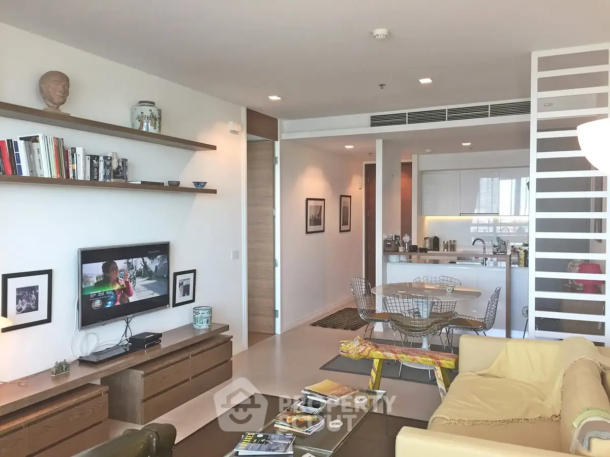 Modern living room with open kitchen, stylish decor, and ample natural light.