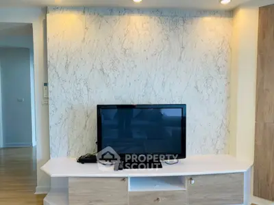 Modern living room with stylish TV setup and elegant marble accent wall.