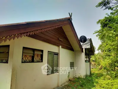 Charming single-story home with rustic wooden eaves and lush greenery, perfect for nature lovers.