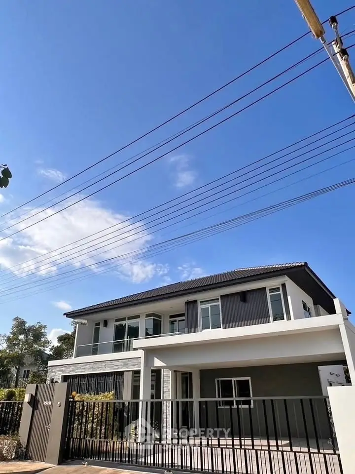 Modern two-story house with sleek design and spacious balcony under clear blue sky.