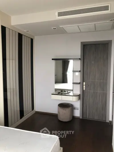 Modern bedroom with sleek design and built-in wardrobe, featuring a stylish vanity area.