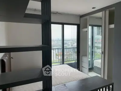 Modern bedroom with city view and balcony access in high-rise apartment.