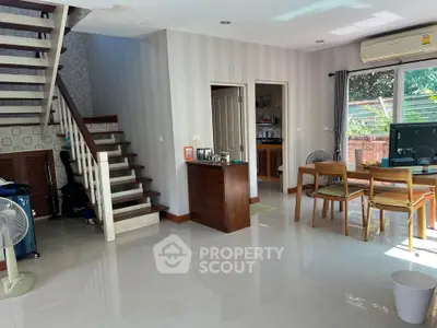 Spacious living room with modern decor and natural light, featuring a staircase and dining area.