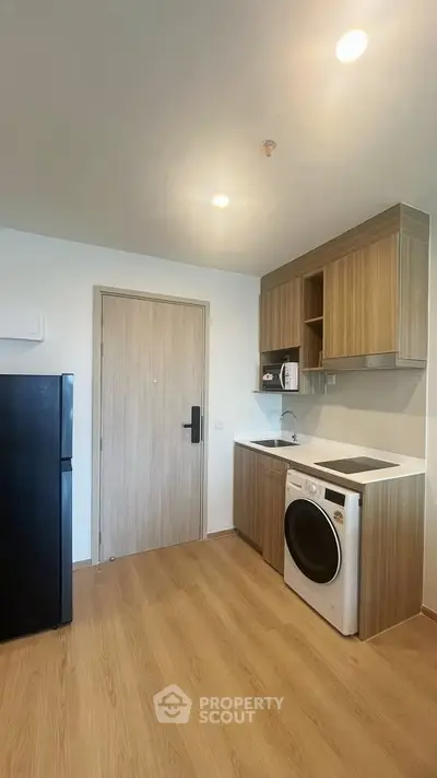 Modern kitchen with wooden cabinets, washing machine, and sleek appliances.