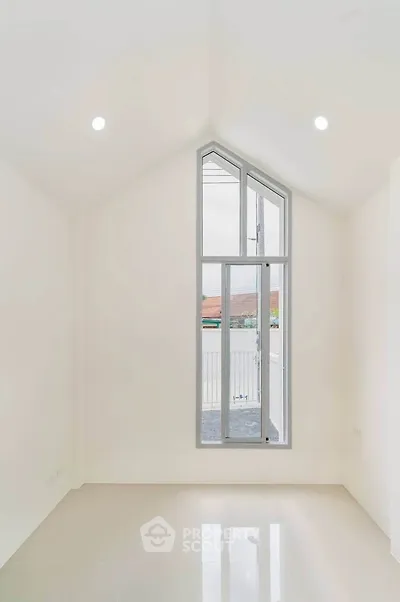 Bright minimalist room with high ceiling and large window, perfect for modern living.