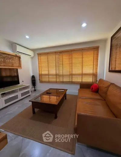 Cozy living room with leather sofa, large window, and modern decor