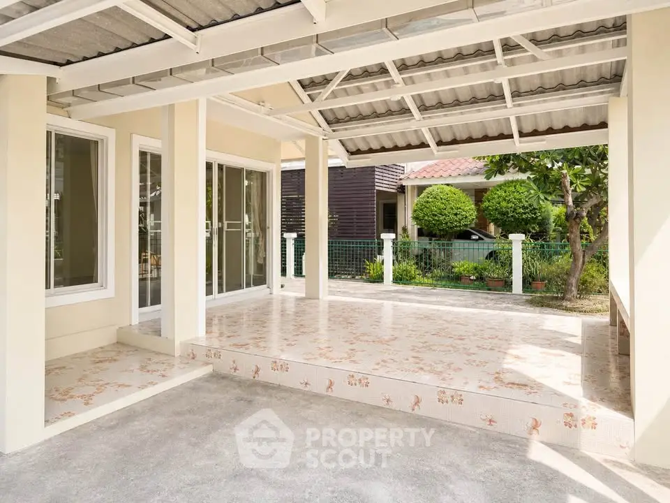 Spacious covered patio with tiled flooring and garden view, perfect for outdoor relaxation.