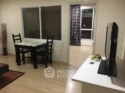 Modern living room with dining area and open view to another room, featuring sleek furniture and wooden flooring.