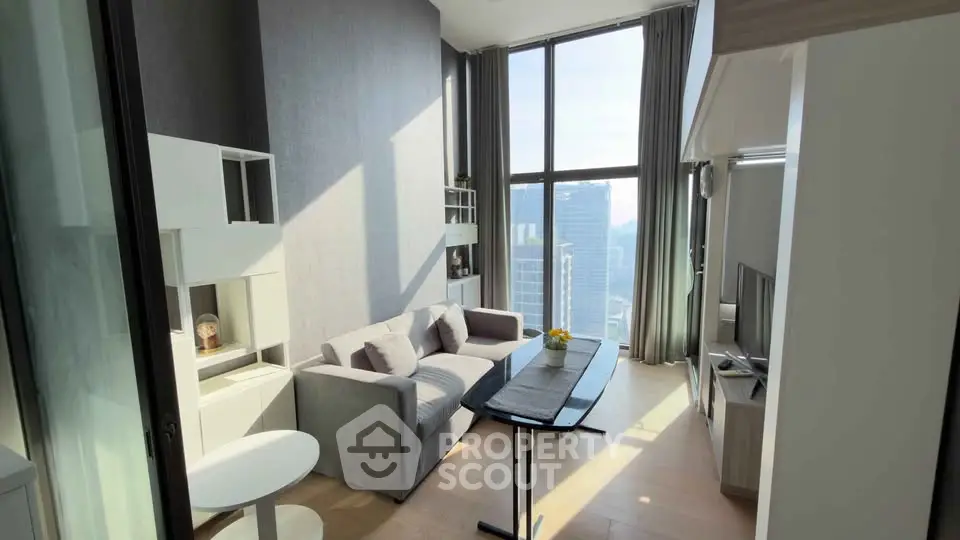 Modern living room with high ceiling and city view, featuring sleek furniture and large windows.