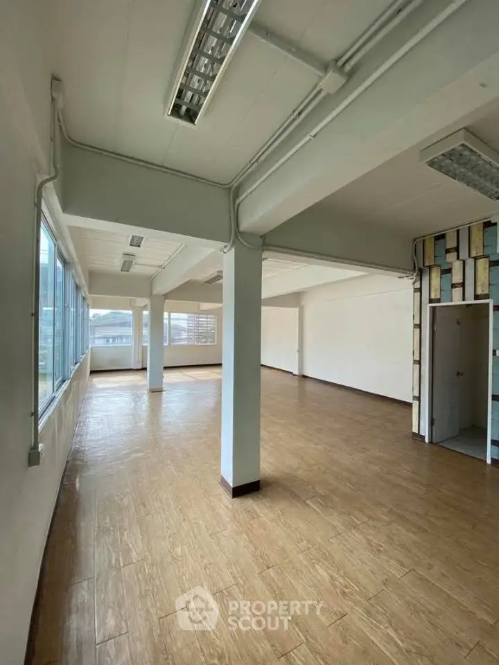 Spacious open-plan office space with large windows and wooden flooring, ideal for modern businesses.