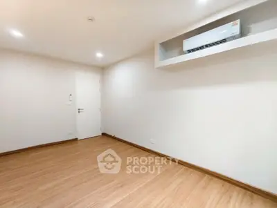 Spacious empty room with wooden flooring and air conditioning, perfect for customization.