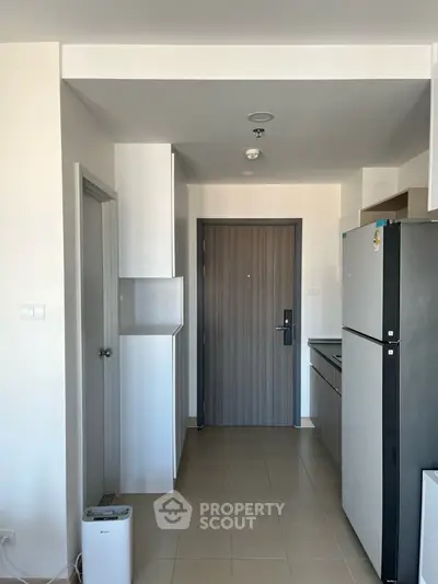Modern apartment entrance with sleek kitchen and stainless steel fridge