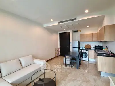 Modern open-layout living room with kitchen, featuring sleek furniture and contemporary design.