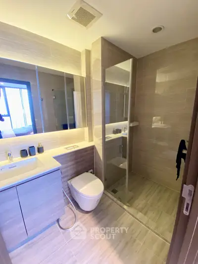 Modern bathroom with glass shower and sleek vanity in contemporary apartment.