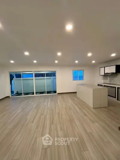 Spacious open-plan living room with modern kitchen and balcony access