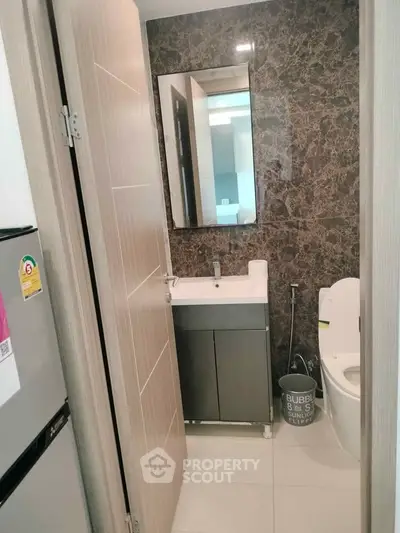 Modern bathroom with sleek design and compact layout, featuring a stylish sink and toilet.