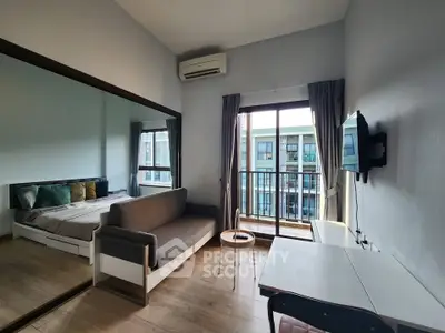Modern studio apartment with balcony, featuring a cozy living area and large mirror for spacious feel.