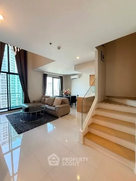 Spacious modern living room with large windows and elegant staircase in a high-rise apartment.