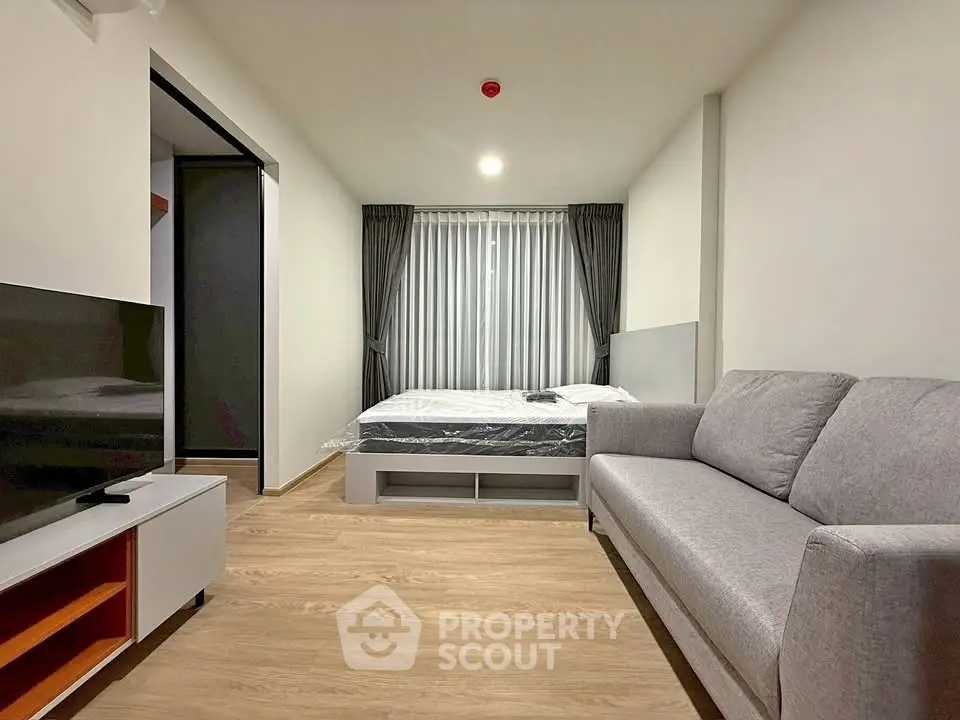 Modern studio apartment with cozy living area and bedroom, featuring sleek furniture and natural light.