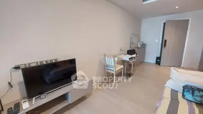 Modern bedroom with TV and workspace, featuring minimalist decor and neutral tones.