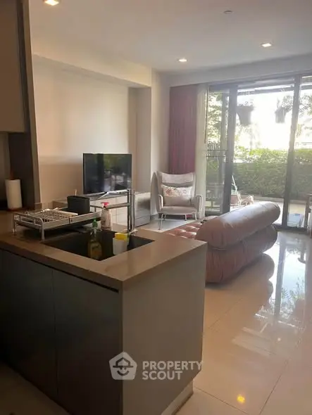 Modern living room with open kitchen and garden view, featuring sleek furniture and natural light.