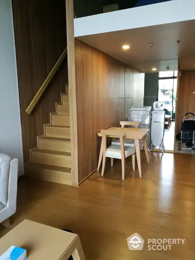 Modern duplex apartment with elegant wooden staircase and sleek furniture, featuring a bright and airy living space with natural light.