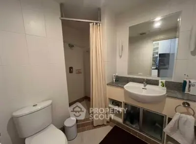 Modern bathroom with shower, sink, and toilet in a sleek real estate property.