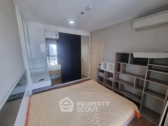 Modern bedroom with built-in wardrobe and air conditioning in urban apartment.