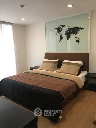 Modern bedroom with stylish decor and world map artwork, featuring a cozy bed and natural light.