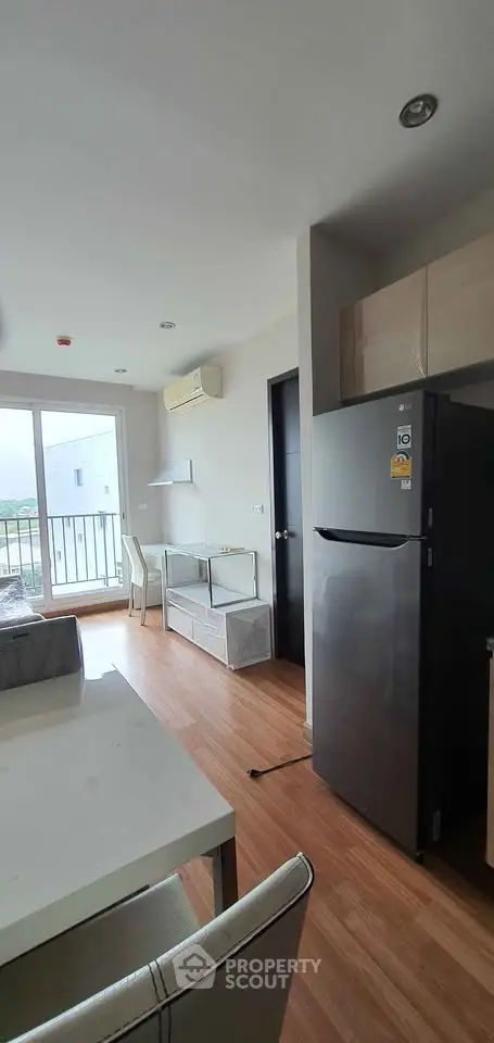 Modern apartment interior with balcony view, sleek furniture, and wooden flooring.