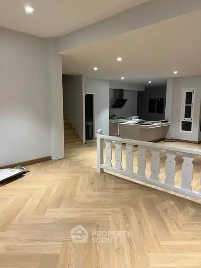 Spacious open-plan living area with modern kitchen and elegant wooden flooring.