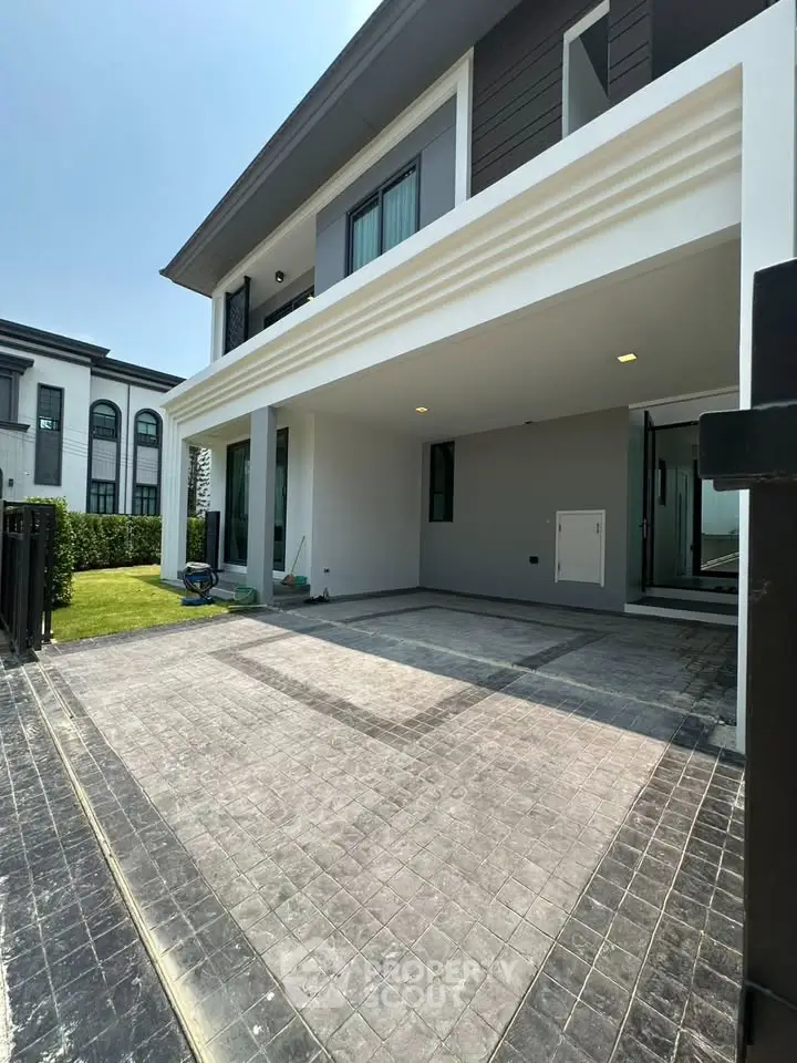 Modern two-story house with spacious driveway and lush green lawn, perfect for family living.