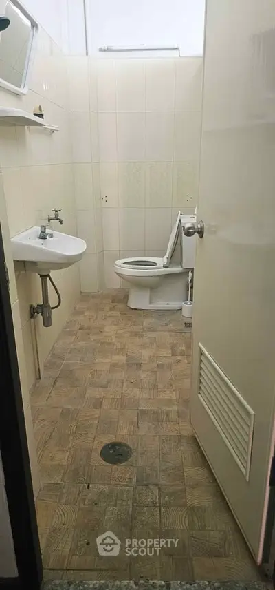Compact bathroom with tiled floor and basic fixtures, ideal for small spaces.