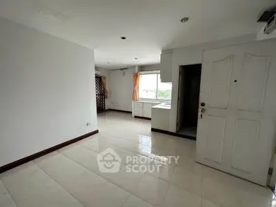 Spacious unfurnished apartment with tiled floors and large window for natural light.