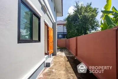 Charming side view of modern home with spacious outdoor walkway and lush greenery.