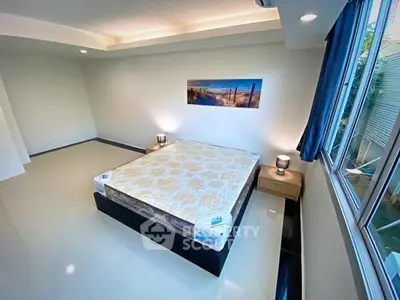 Spacious bedroom with large window and modern decor in a serene setting.