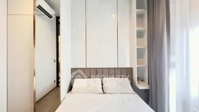 Modern bedroom with elegant design and natural light, featuring built-in shelves and air conditioning.