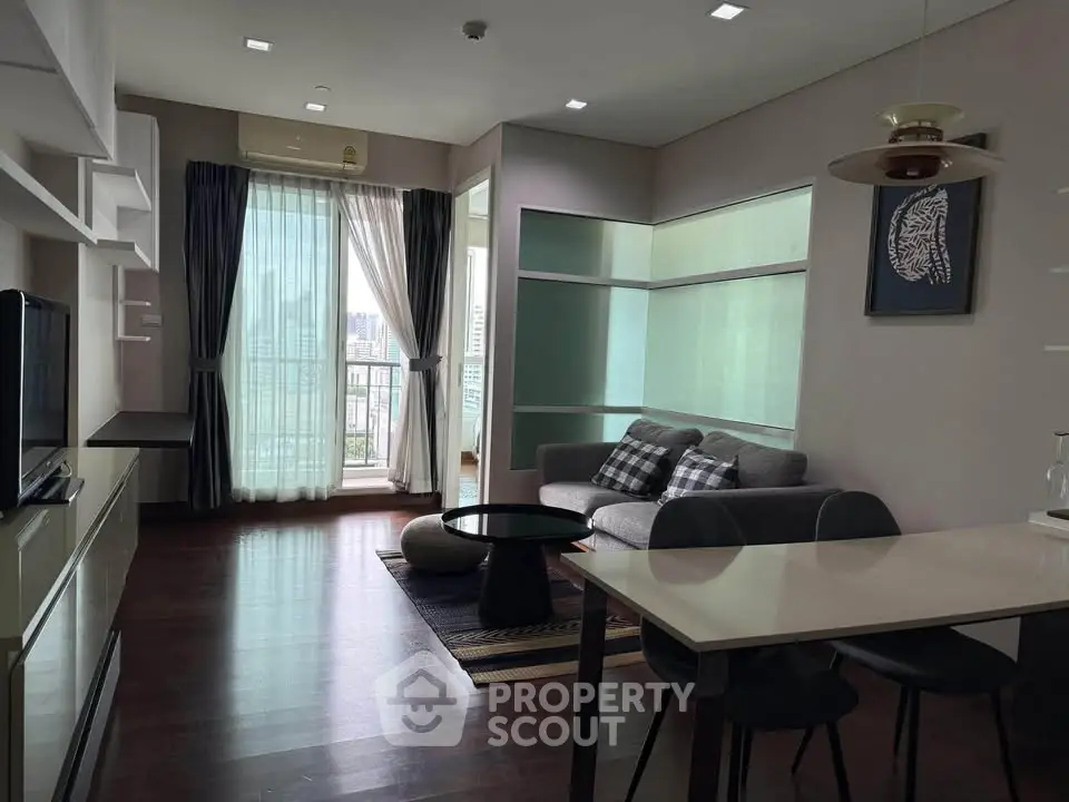 Modern living room with city view, stylish furniture, and natural light in a high-rise apartment.