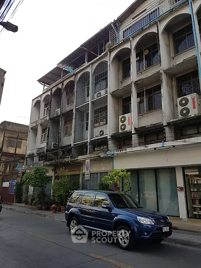 Urban street view of a multi-story building with balconies and parked car.