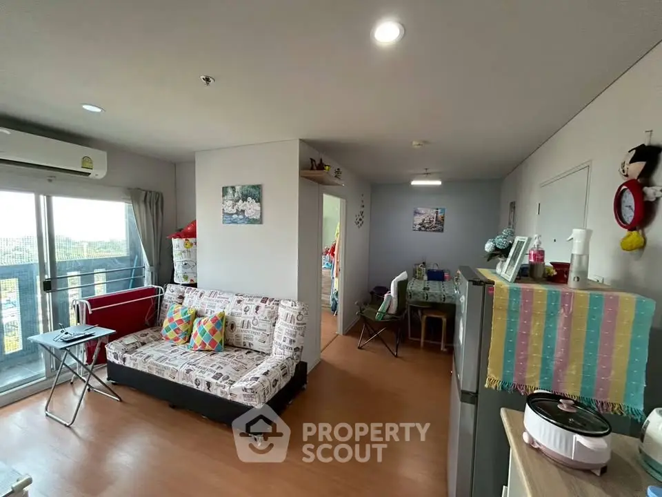 Modern living room with balcony view, featuring cozy seating and stylish decor in a bright apartment.