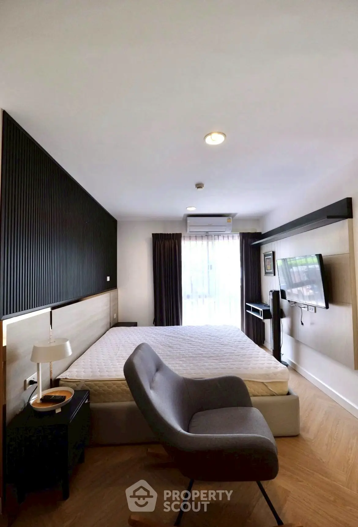Modern bedroom with stylish decor, featuring a cozy bed, sleek furniture, and natural light from large windows.