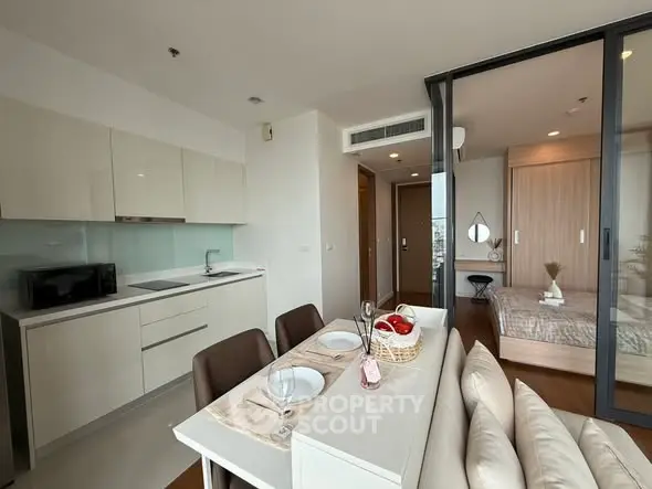 Modern open-plan kitchen and dining area with sleek design and cozy bedroom view.