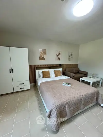 Spacious bedroom with modern decor, featuring a cozy bed, wardrobe, and stylish artwork, perfect for relaxation.