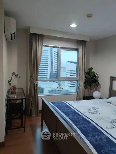 Cozy bedroom with city view, featuring modern decor and natural light.