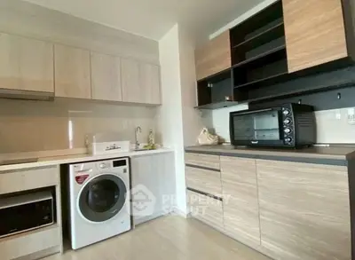 Modern kitchen with sleek cabinetry, washing machine, and countertop oven in a stylish apartment.