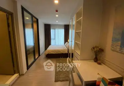 Cozy bedroom with study area and large mirrored closet in modern apartment.