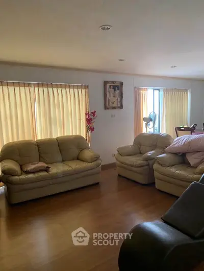 Spacious living room with cozy leather sofas and natural light from large windows.