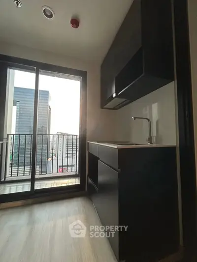 Modern kitchen with sleek black cabinetry and city view balcony in high-rise apartment.