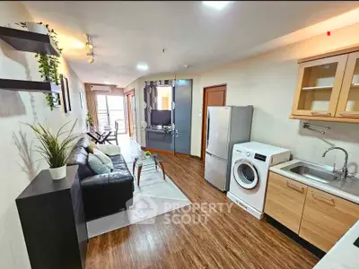 Modern living room with open kitchen, featuring sleek appliances and stylish decor.